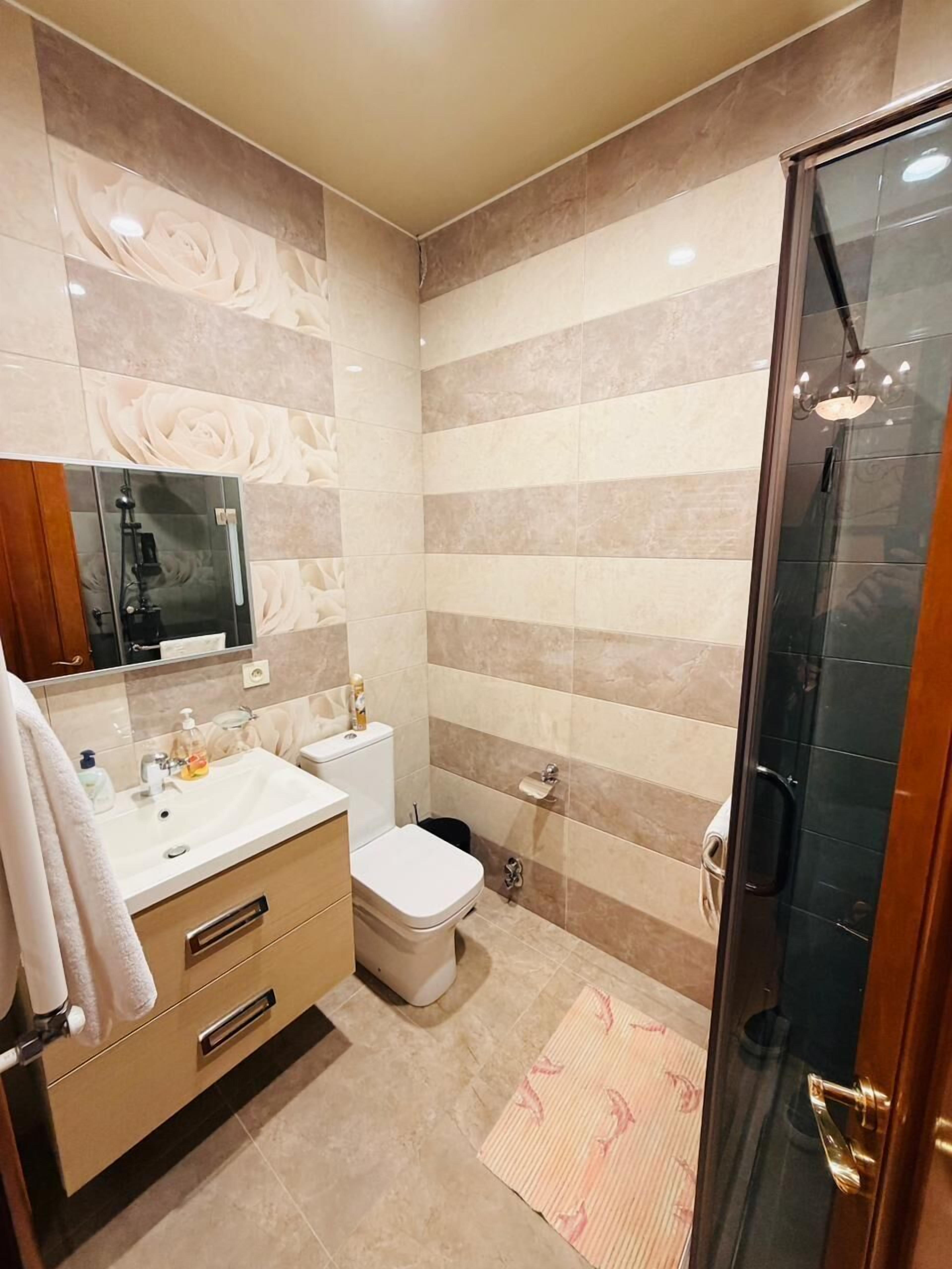 A bathroom with a vanity, toilet, shower, and a glass-enclosed shower area.