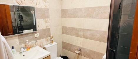 A bathroom with a vanity, toilet, shower, and a glass-enclosed shower area.