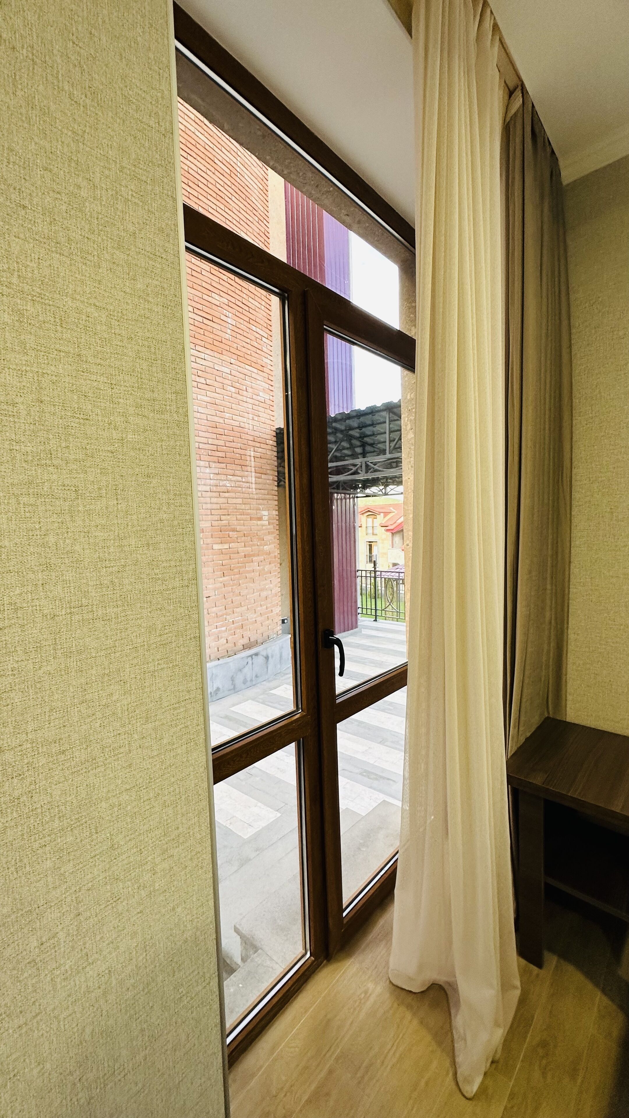 A room with a sliding glass door leading to an outdoor area with a brick wall and a metal fence.