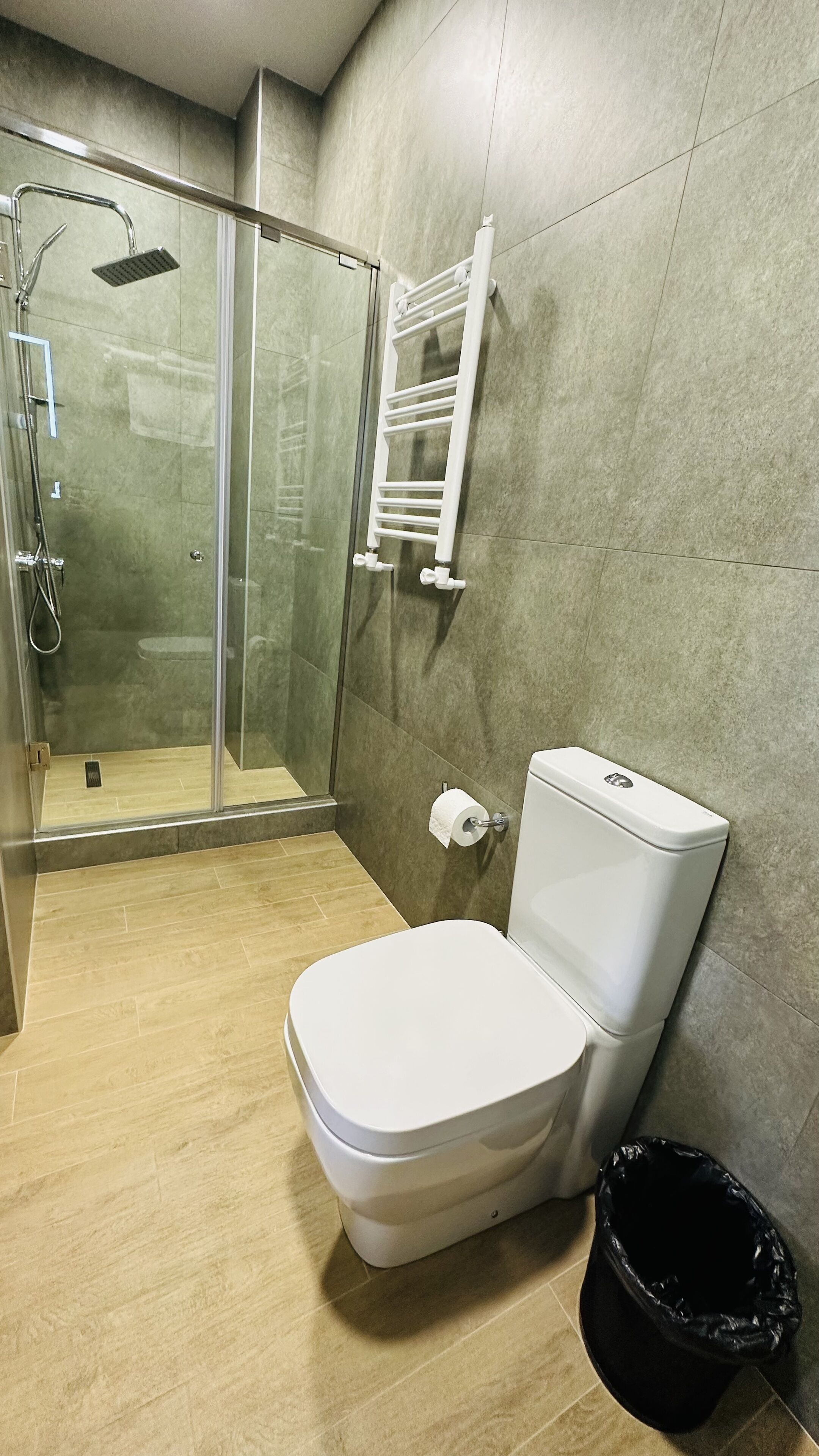 A bathroom with a toilet, a glass shower enclosure, and a towel rack.