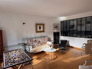Una habitación con cama, una mesa redonda, una silla, un sofá y un ventanal grande.