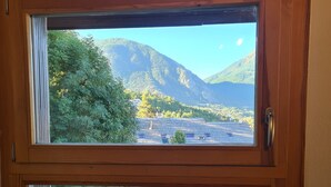 A wooden-framed window with a view of a mountain and trees. - Apartment with view of Prorel (Briançon)