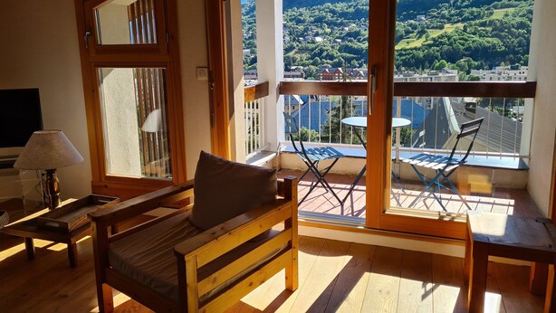 A balcony with a wooden bench, a table, and chairs. - Apartment with view of Prorel (Briançon)