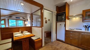 A compact kitchen with wooden cabinetry, a built-in microwave, and a gas stove. - Apartment with view of Prorel (Briançon)