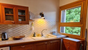 A kitchen with wooden cabinets, a built-in dishwasher, a sink with a dish rack, and a window with a view of greenery. - Apartment with view of Prorel (Briançon)