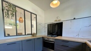 A modern kitchen with grey cabinets, a black stove, and a marble backsplash. - Spacious cocoon with pool in La Rochelle (La Rochelle)
