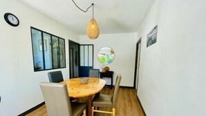 A dining area with a round wooden table, four chairs, a hanging light fixture, and a clock on the wall. - Spacious cocoon with pool in La Rochelle (La Rochelle)