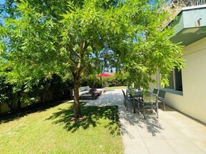 Ein Patio mit Baum, Gartenmöbeln und einem Gebäude.