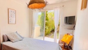 A bedroom with a bed, a TV mounted on the wall, and a window with curtains. - Spacious cocoon with pool in La Rochelle (La Rochelle)