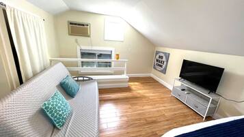 A bedroom with a bed, a TV, a white dresser, a window, and a ceiling fan.