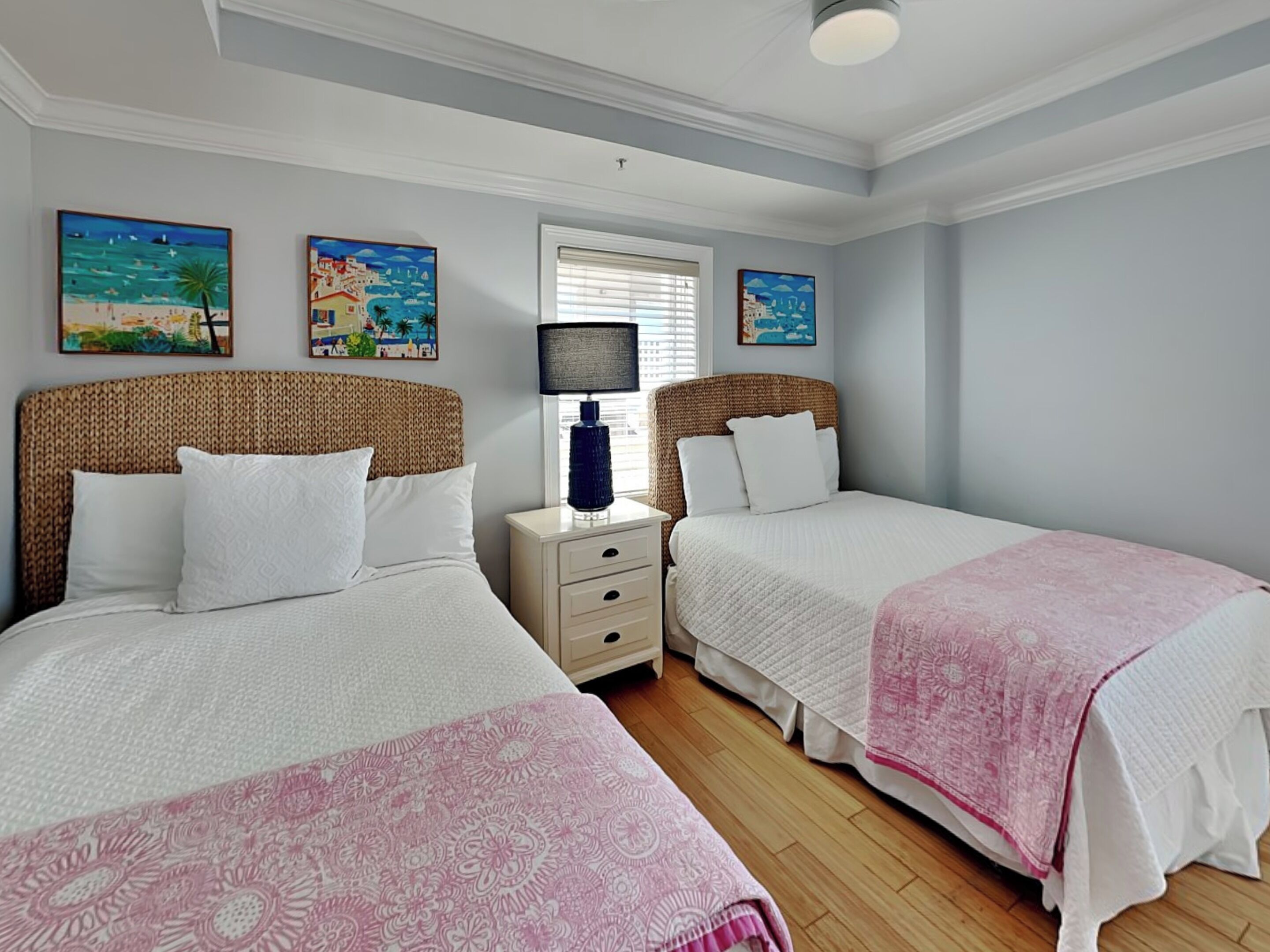A bedroom with two beds, a nightstand, and wall art.