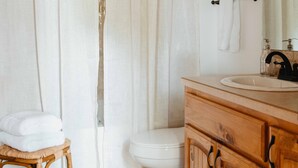 Un bagno con un mobile lavabo in legno, un water e una tenda per la doccia.