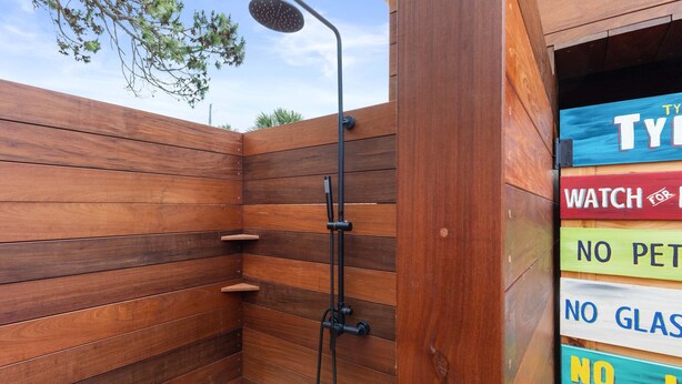 A wooden shower enclosure with a handheld showerhead and a sign with partially visible text. - Tybrisa Treasure by Tybee Vacation Rentals (Tybee Island)