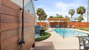 A backyard with a wooden deck, a pool, and a covered seating area. - Tybrisa Treasure by Tybee Vacation Rentals (Tybee Island)
