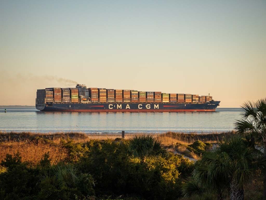 A large cargo ship with the letters 'CMA CGM' on its side, sailing on a body of water.