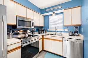 A modern kitchen with stainless steel appliances, white cabinets, and a blue accent wall.
