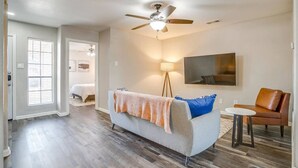 Un salon comprenant un canapé, une table basse, un téléviseur, un ventilateur de plafond et une lampe sur pied.