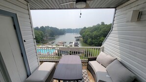 Une terrasse extérieure couverte avec vue sur un lac, une piscine et des bateaux.