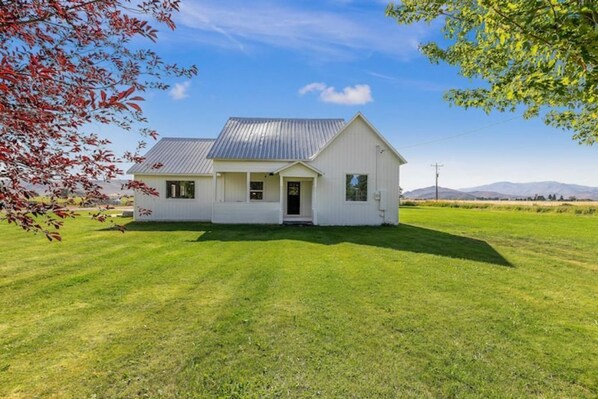 A single-story house with a sloped metal roof, a front porch, and a well-maintained lawn.