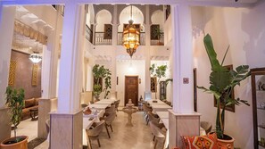 A spacious interior with a central fountain, multiple dining tables, and chairs arranged around it. - Riad Mandana & Spa  (Marrakech)