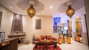 Un amplio vestíbulo con chimenea, una recepción, una escalera y detalles decorativos en las paredes.