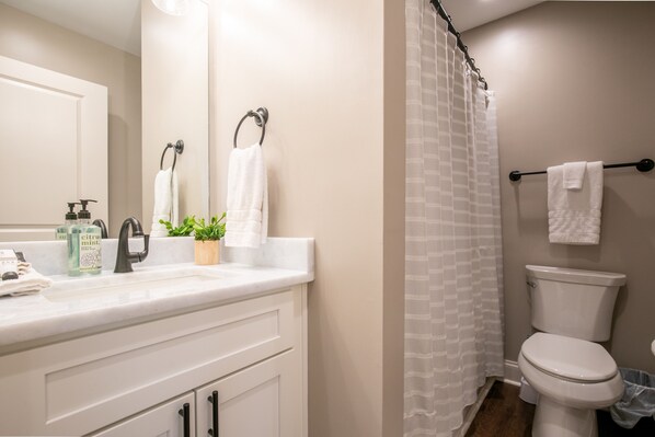 A bathroom with a white sink, a mirror, a toilet, and a shower curtain.