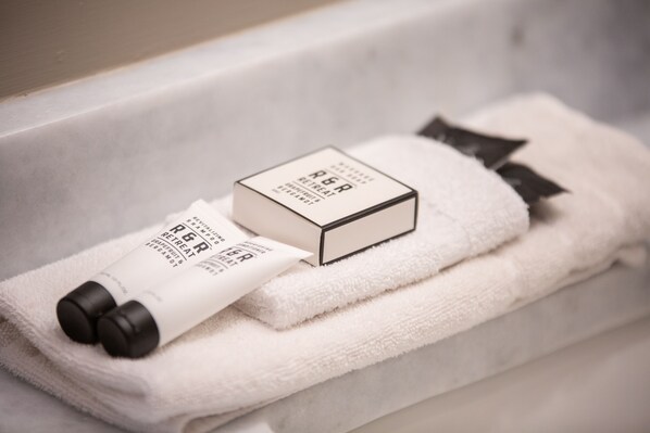 Une salle de bain bien rangée, avec une serviette blanche, une bouteille de shampoing et une boîte de produits de toilette.