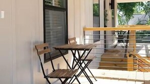 Un terrazzo in legno con tavolo e sedie, una finestra e un lampadario a parete.