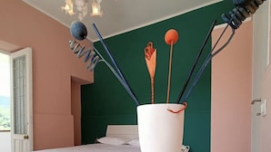 A bedroom with a bed, a white table, and a vase with utensils. - A cozy refuge in the sky (tramonti)
