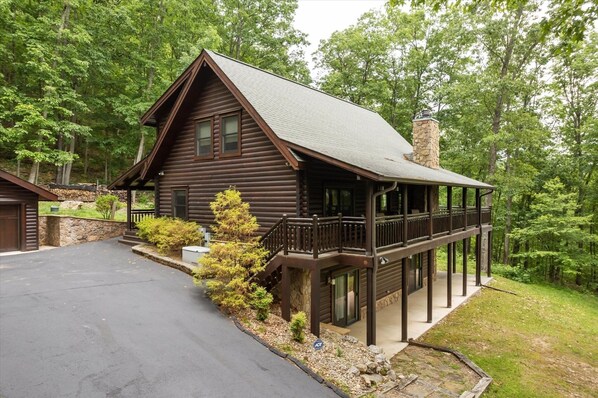 A log cabin with a balcony, surrounded by trees.