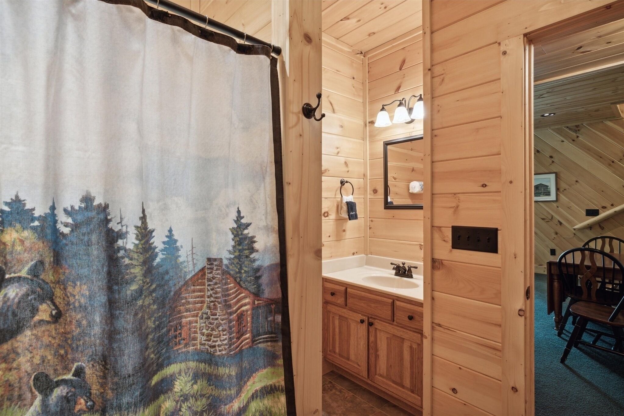 A wooden cabin bathroom with a wooden door, a sink, and a mirror.