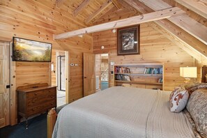 A wooden cabin bedroom with a bed, dresser, bookshelf, and a painting on the wall.