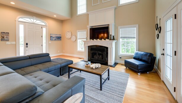 A spacious living room with a fireplace, a sectional sofa, a coffee table, and a blue armchair. - Harkers Island Vacation Rental with Pool Table! (Harkers Island)