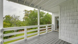 A covered porch with white railings and a view of a green landscape. - Harkers Island Vacation Rental with Pool Table! (Harkers Island)