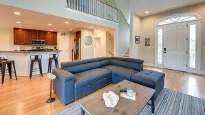 A spacious living area with a large sectional sofa, a dining table, and a kitchen area with a bar. - Harkers Island Vacation Rental with Pool Table! (Harkers Island)