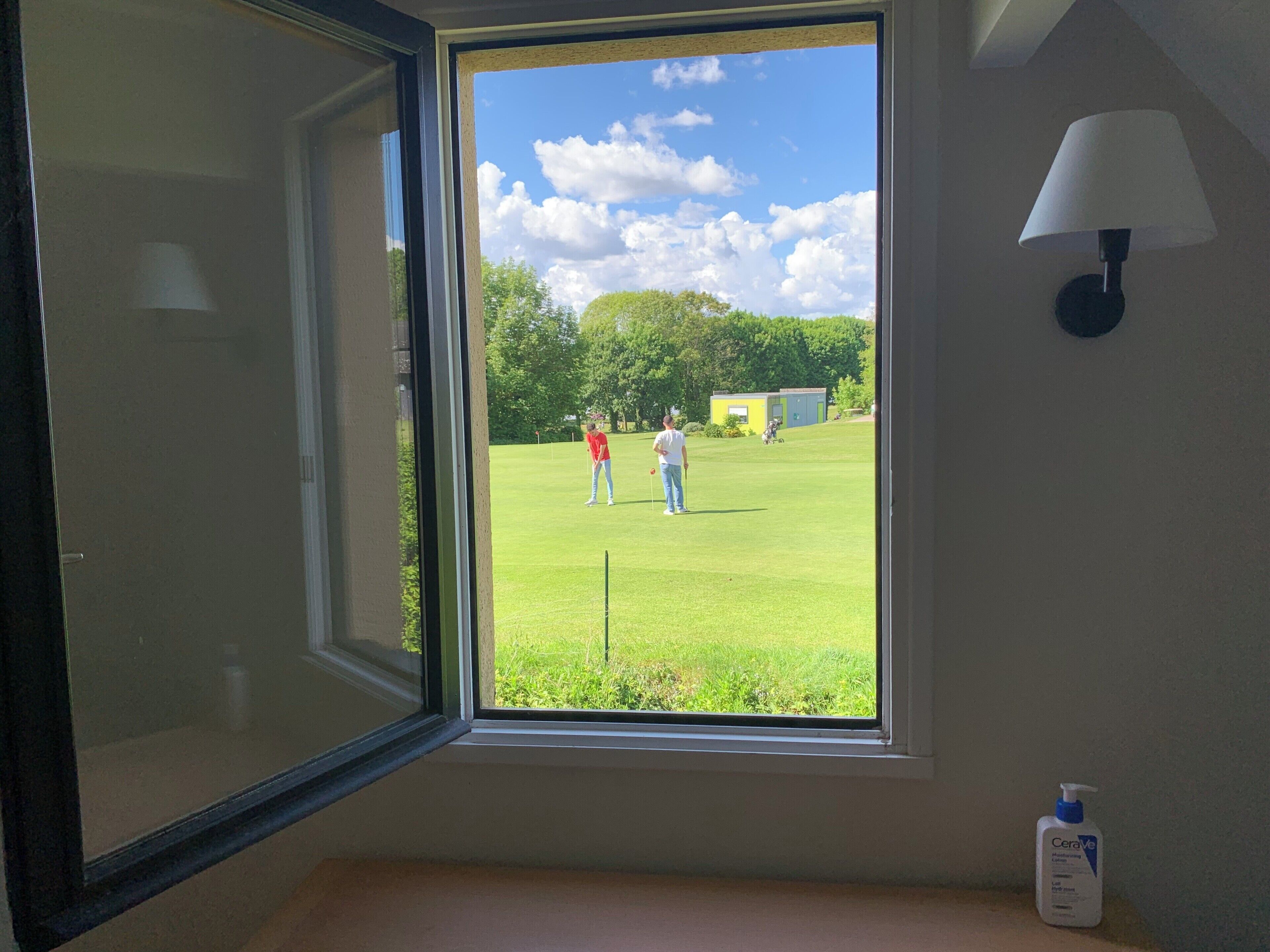 A room with a window overlooking a golf course.