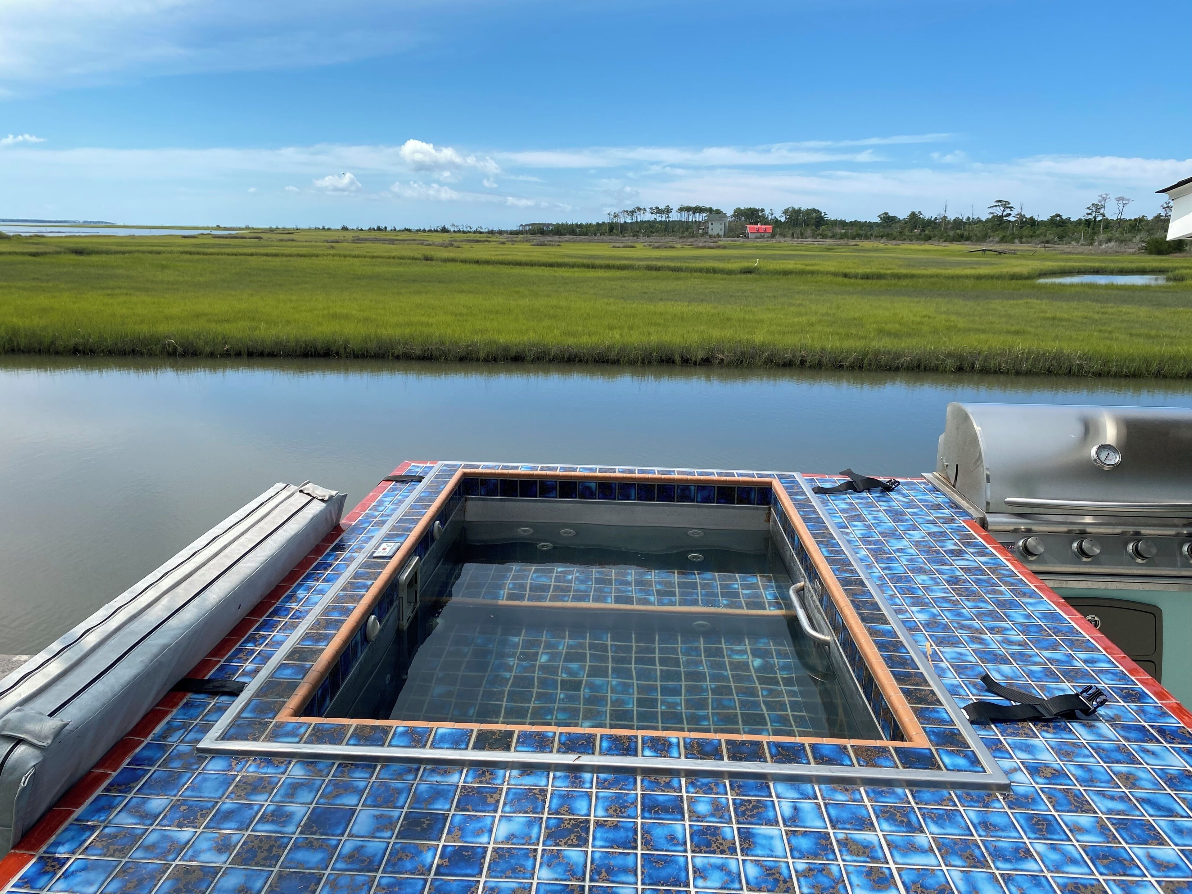 Un barco con cubierta de baldosas, jacuzzi y parrilla.