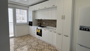 Una cocina moderna con armarios blancos, horno integrado y refrigerador.