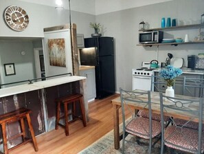 Kitchen area with central island, microwave, stove, sink, and shelves for kitchen essentials.