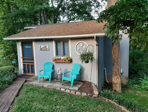 Relax on the porch with Adirondack chairs and a lantern, surrounded by a serene garden.