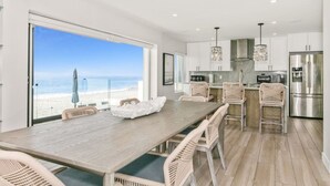 Una cucina moderna con mobili bianchi, elettrodomestici in acciaio inossidabile e sedie in vimini.