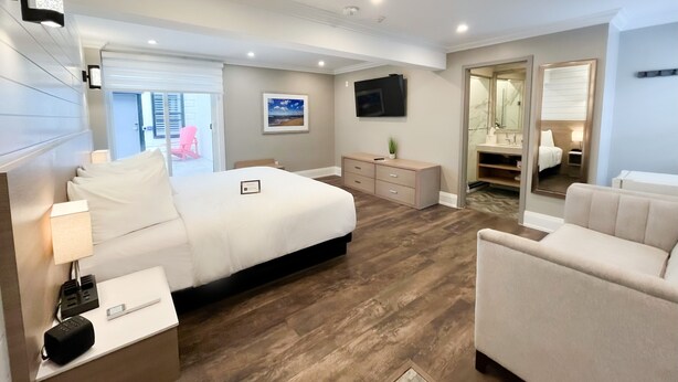 Een moderne hotelkamer met een groot bed, een bureau, een stoel, een dressoir, een televisie en een badkamer zichtbaar door een geopende deur.