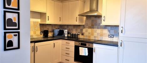 A kitchen with white cabinets, a microwave, a stove, and a ceiling light fixture.