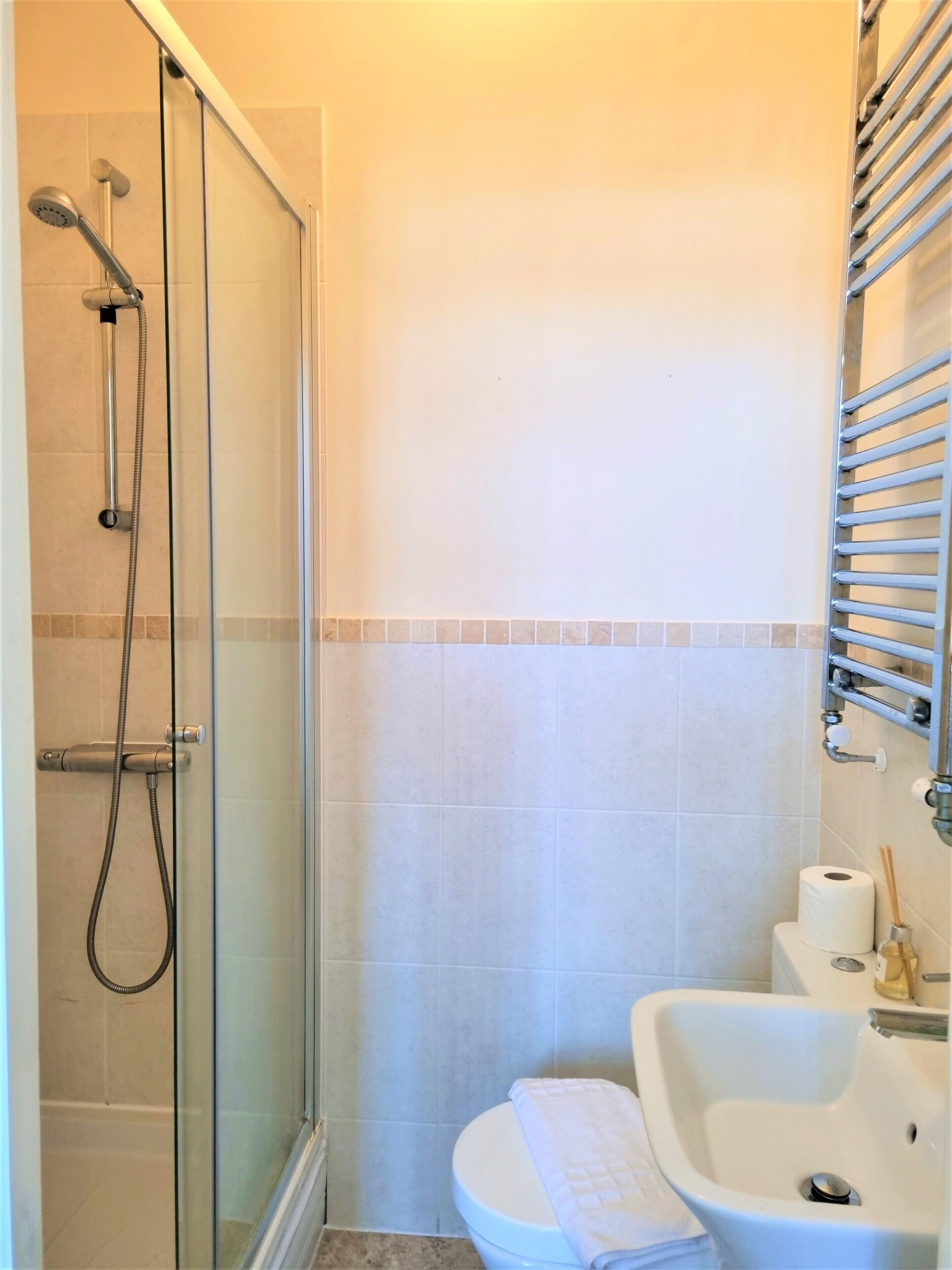 Ein Badezimmer mit einer gläsernen Duschkabine, einem weißen Waschbecken und einer Toilette.
