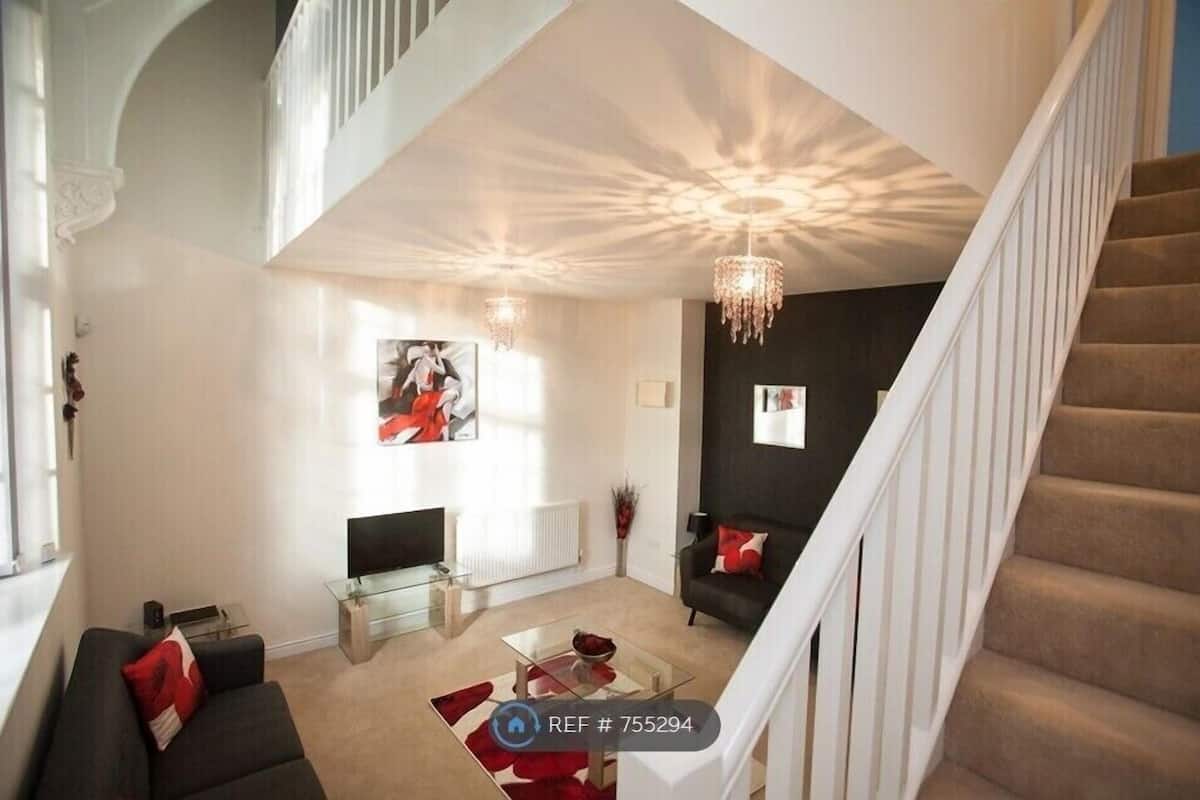 Een moderne woonkamer met een trap, een open haard en een kroonluchter.