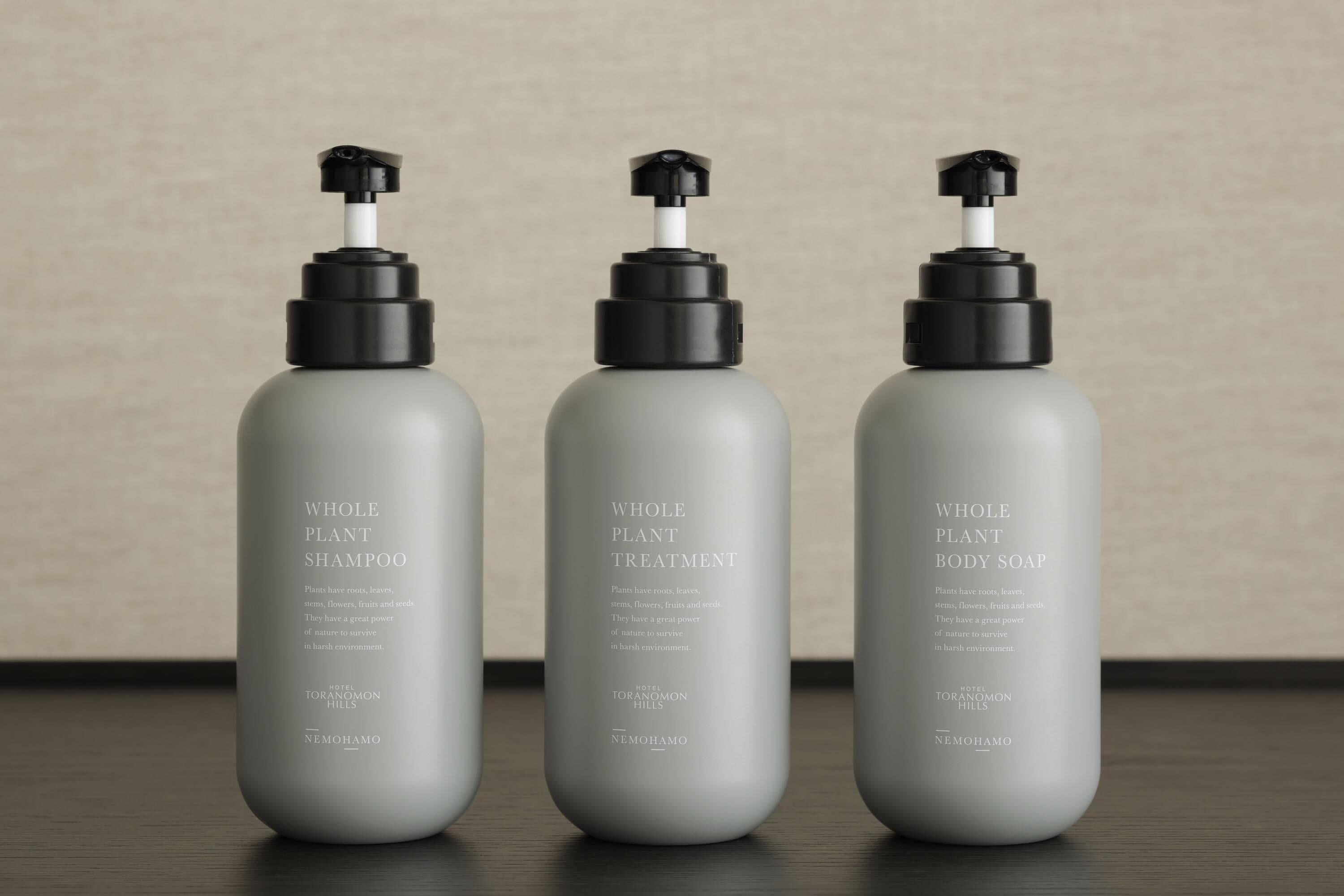 Three grey bottles of NEMOHAMO products on a wooden surface.