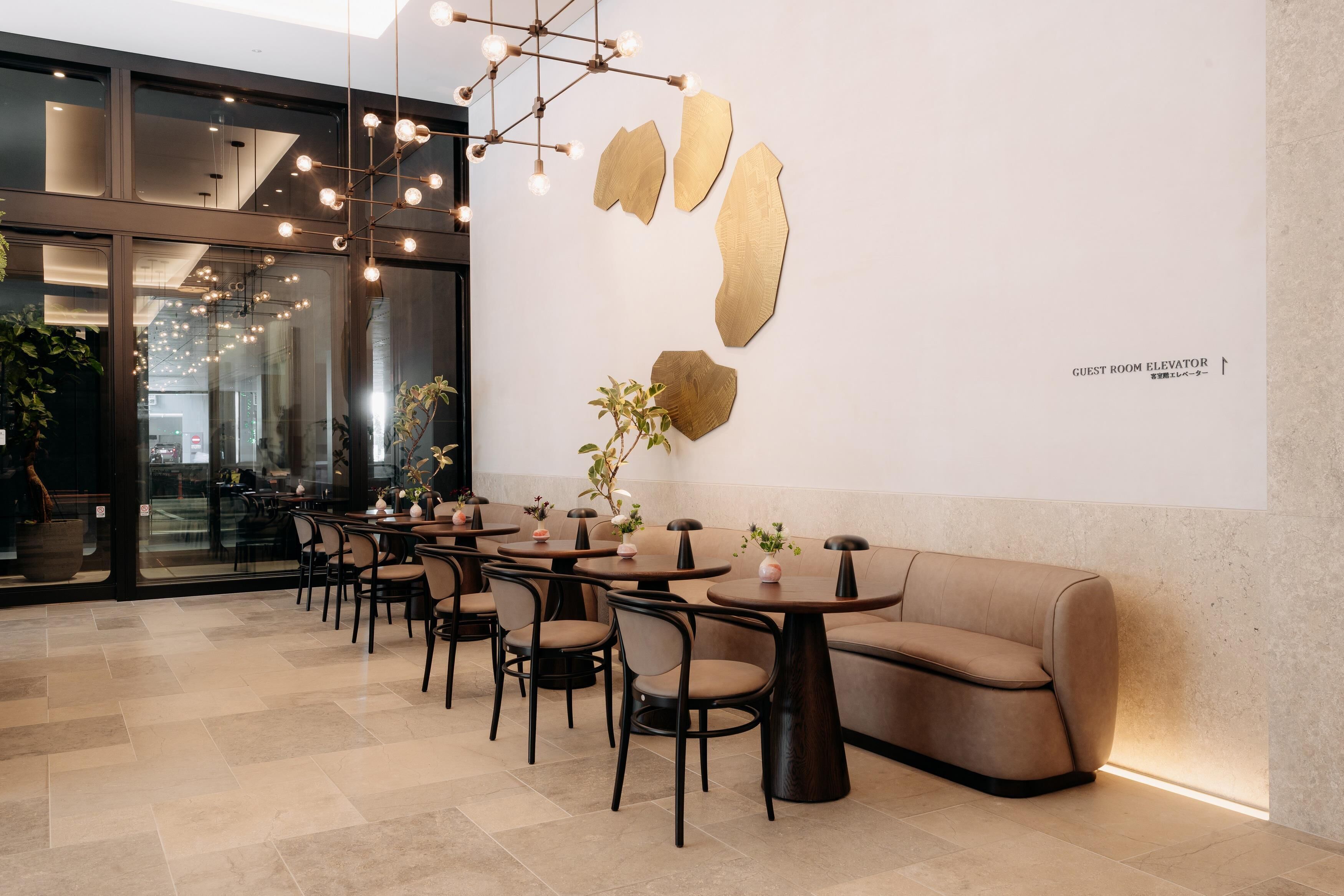 Un intérieur moderne avec des tables rondes, des chaises, un canapé et des œuvres d’art abstraites accrochées aux murs.