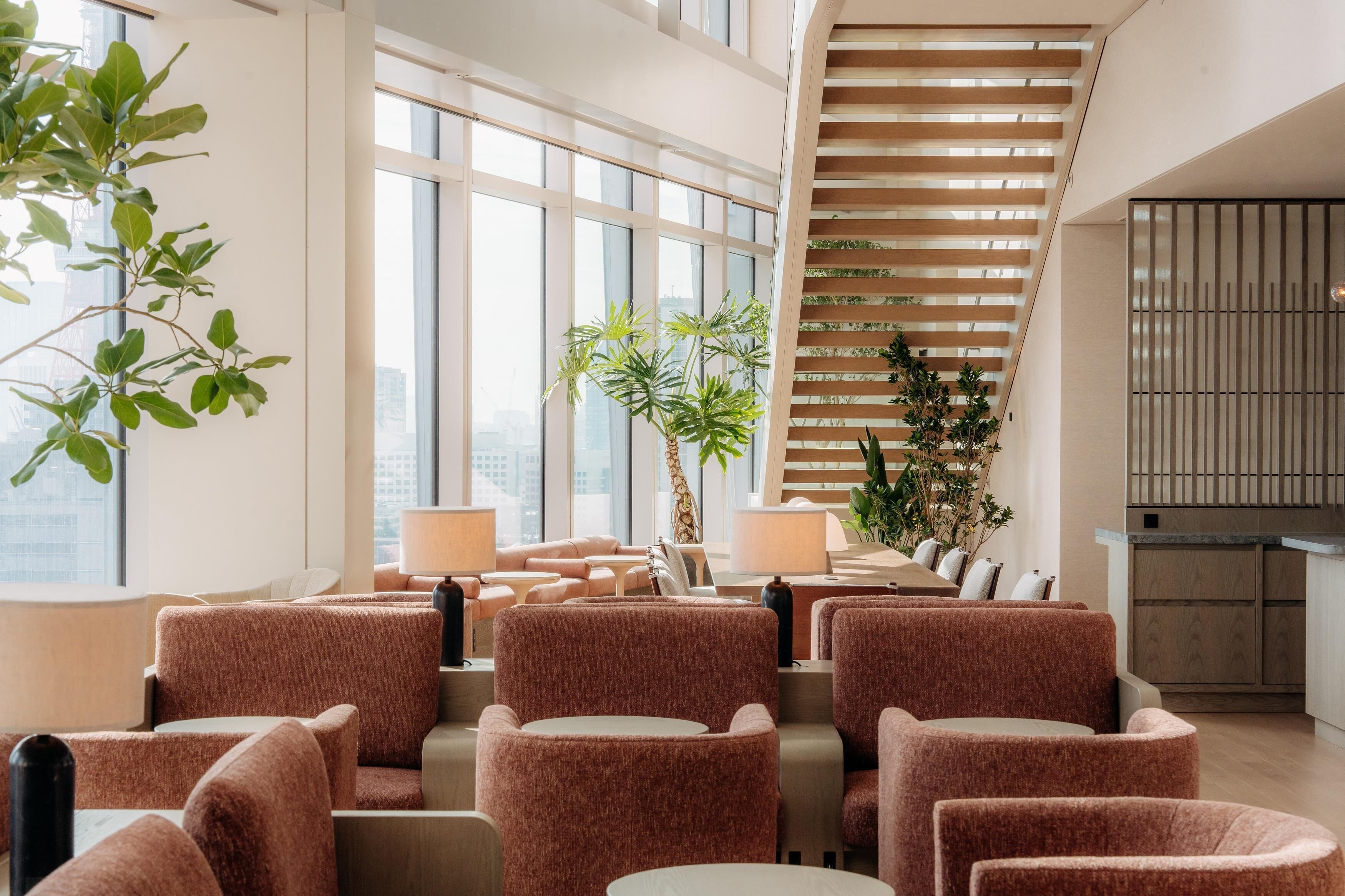 A modern interior with seating, large windows, and a staircase.