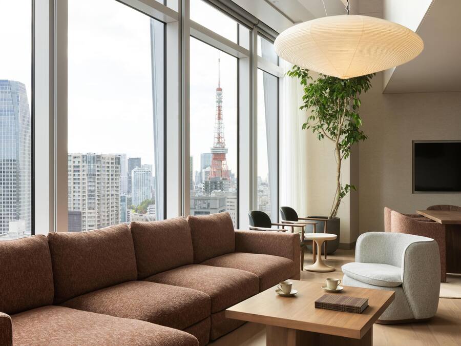 A modern living room with a large window, a sofa, a table, and a hanging plant.