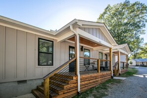 Stroll up to the charming entrance, where a cozy porch invites relaxation with a seating area and railing.